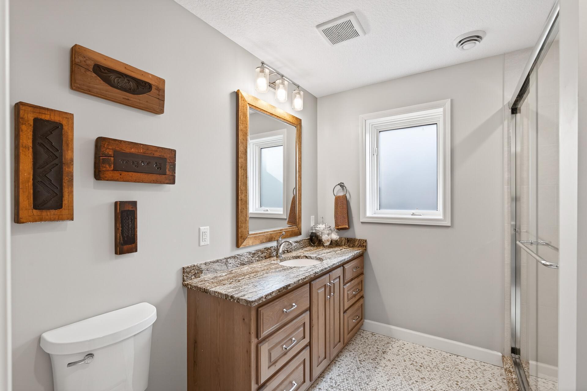 This lower level bathroom offers a larger vanity and privacy-frosted glass for natural light.