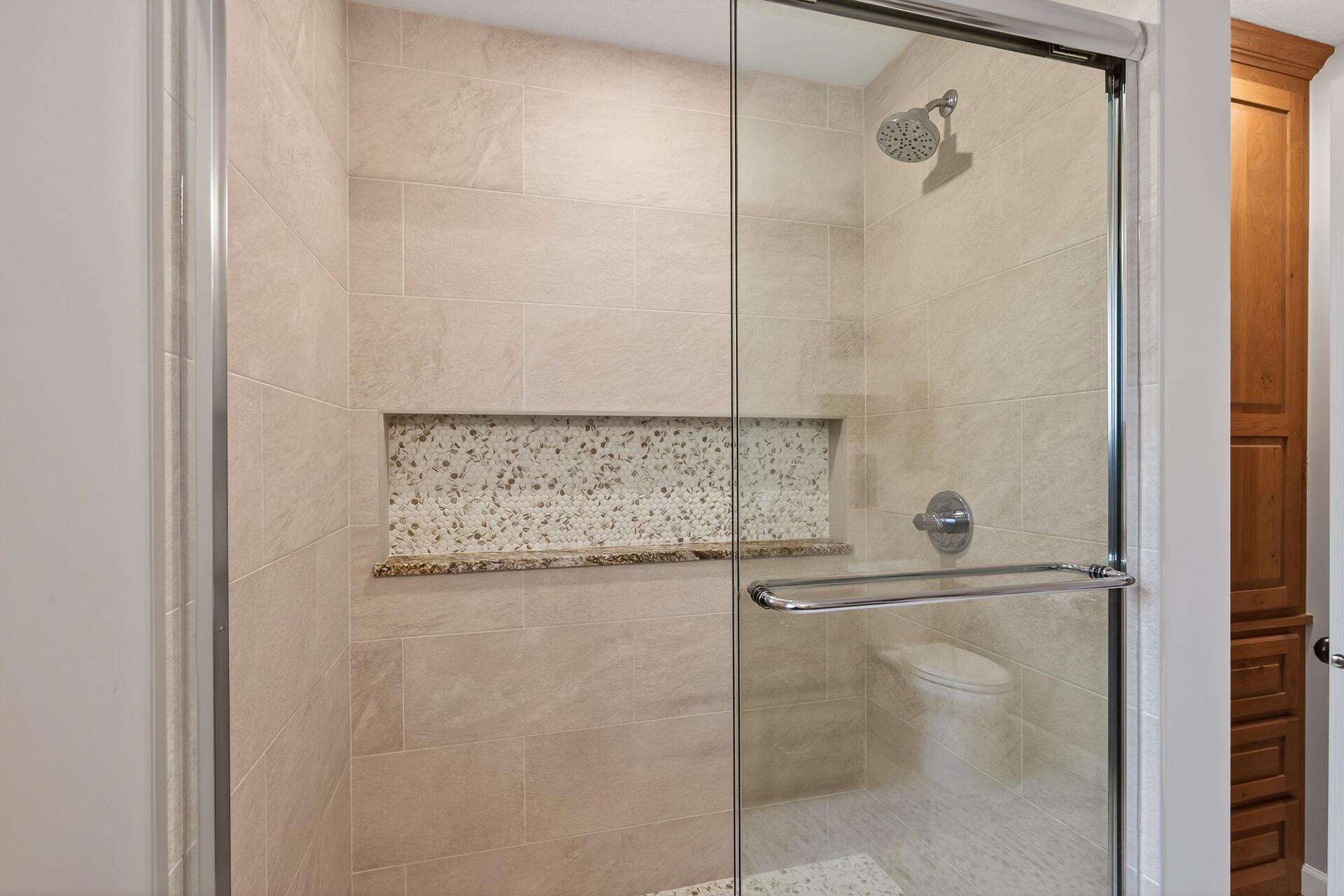 Detailed tile work and a recessed storage shelf highlight this guest bathroom shower.