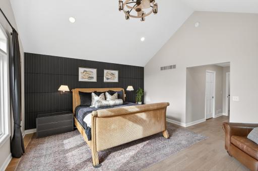 A dramatic dark-toned accent wall adds a bold, contemporary edge to the light-filled primary suite.