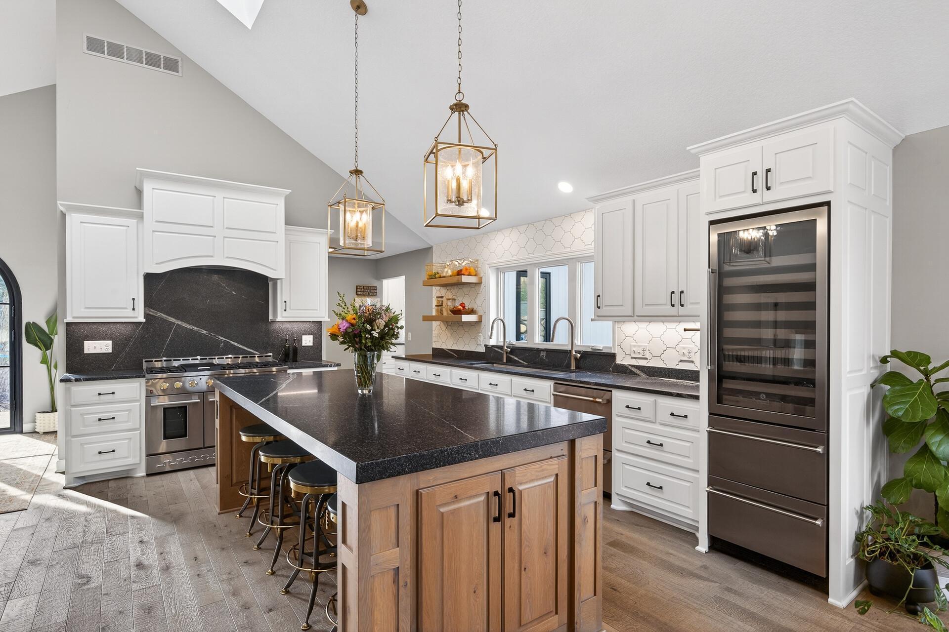 A kitchen equipped for the serious host: 48" dual-oven, professional range with six burners and integrated griddle, and a built-in beverage refrigerator.