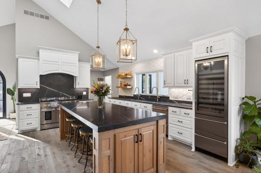 A kitchen equipped for the serious host: 48" dual-oven, professional range with six burners and integrated griddle, and a built-in beverage refrigerator.