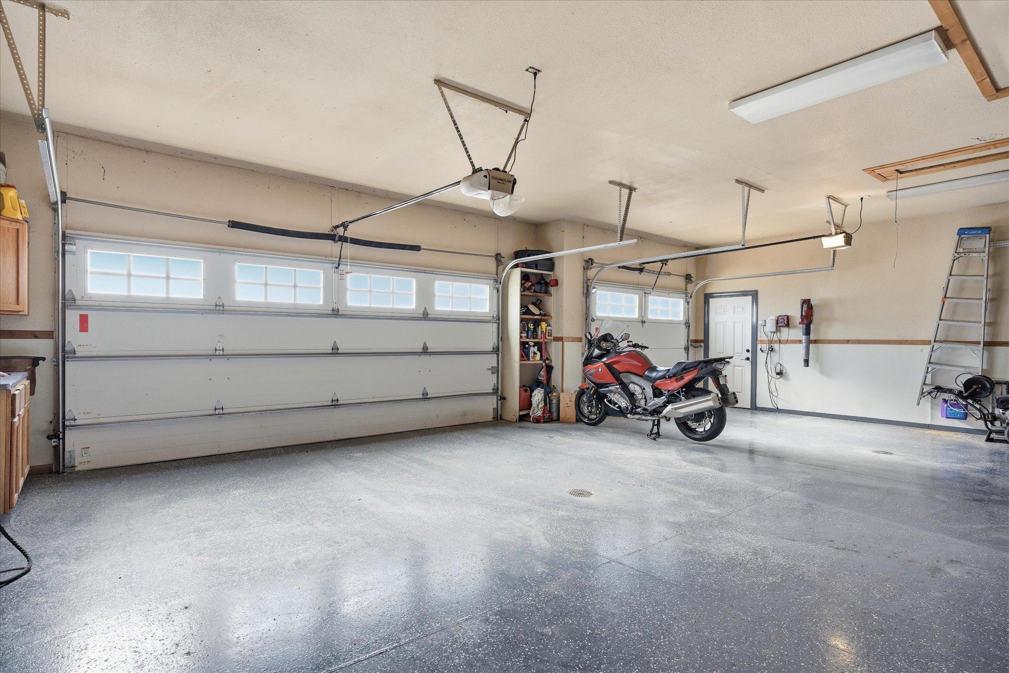 Oversized heated 3-car garage offering excellent natural light, epoxy-coated floors with drains, abundant cabinetry, and extra storage.