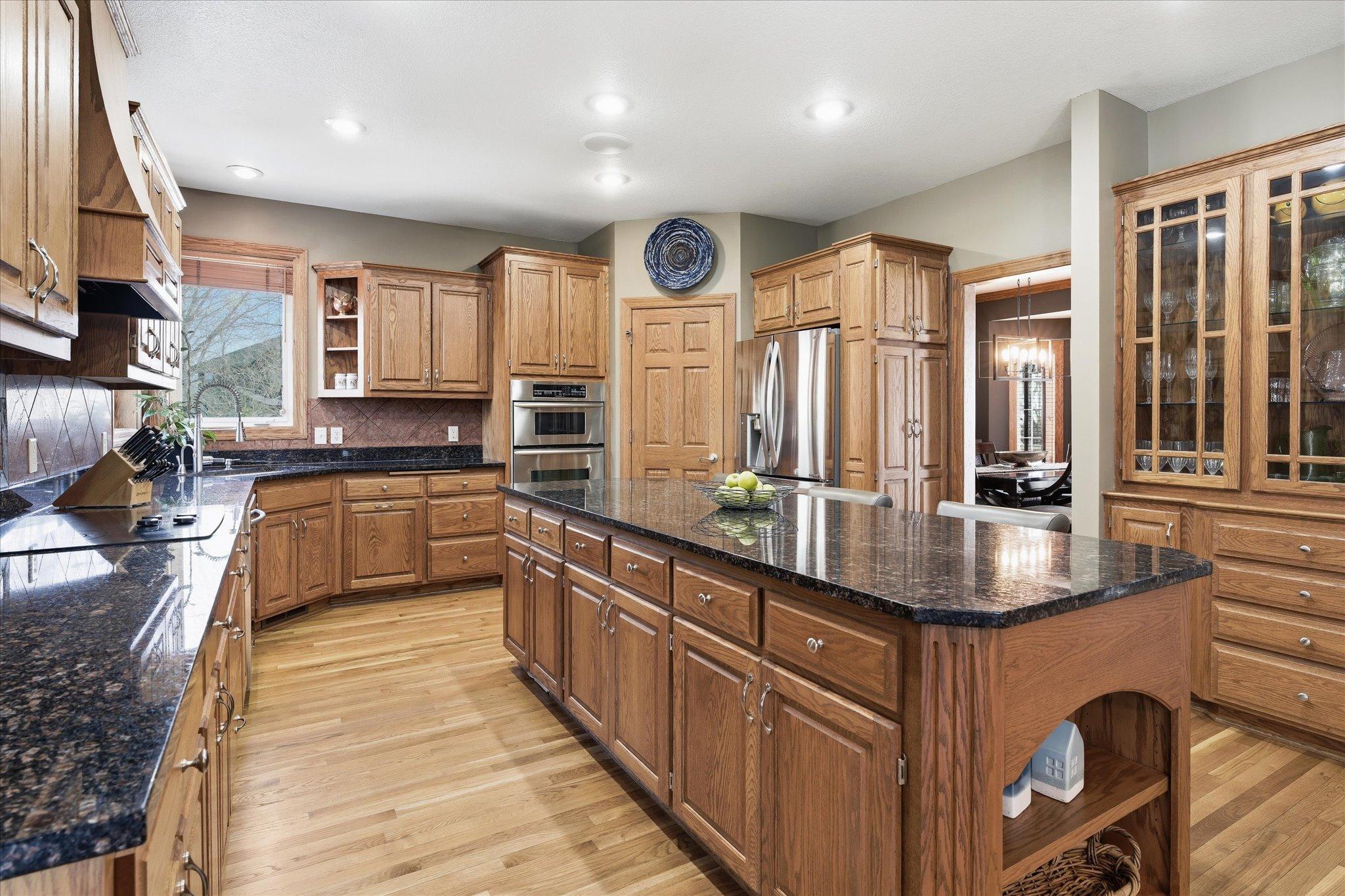 Spacious kitchen designed for both function and style with granite countertops, a large center island, stainless steel appliances, cooktop, and double oven.