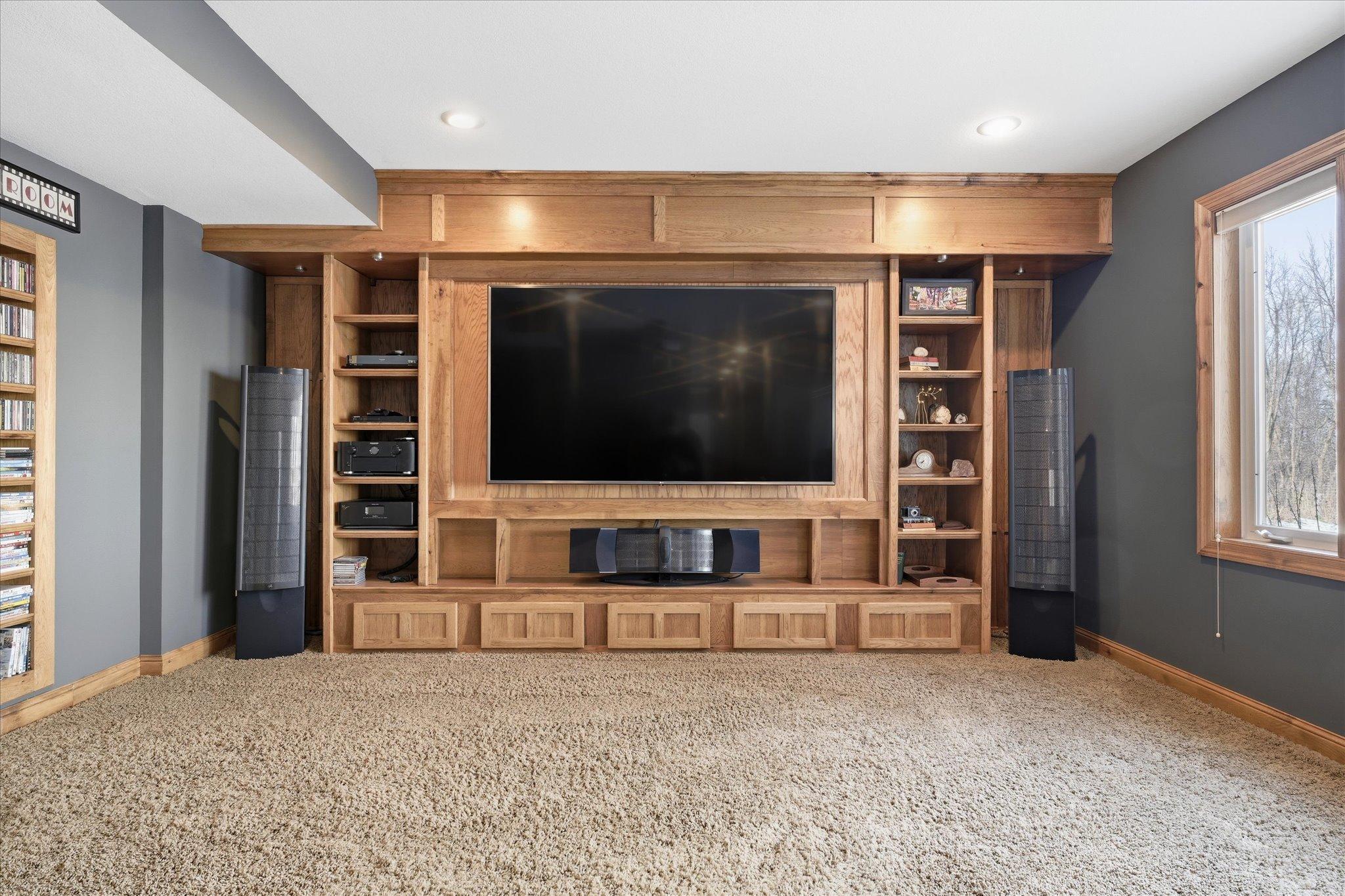 Lower-level media/theater room featuring a projector and built-in shelving, creating the perfect space for movie nights and entertainment. (Speakers are not included.)