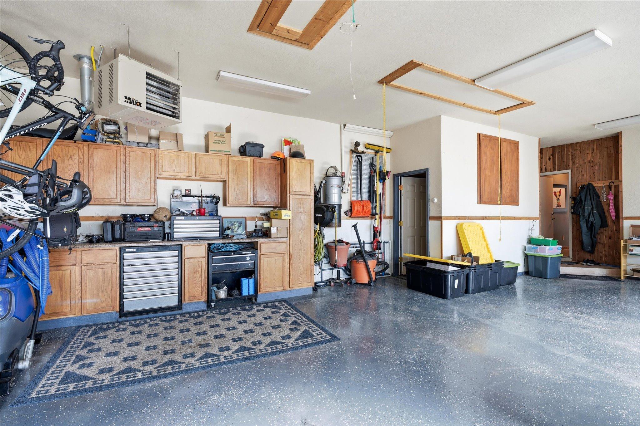 Oversized heated 3-car garage offering excellent natural light, epoxy-coated floors with drains, abundant cabinetry, and extra storage.