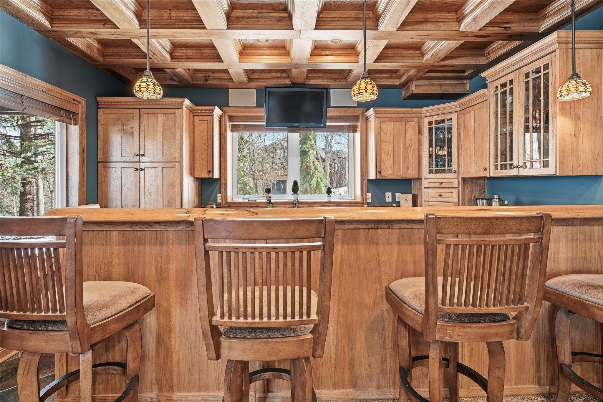 The space is enhanced by elegant lighting, glass display cabinets, and built-in storage, creating a warm and inviting setting for gatherings and game nights.