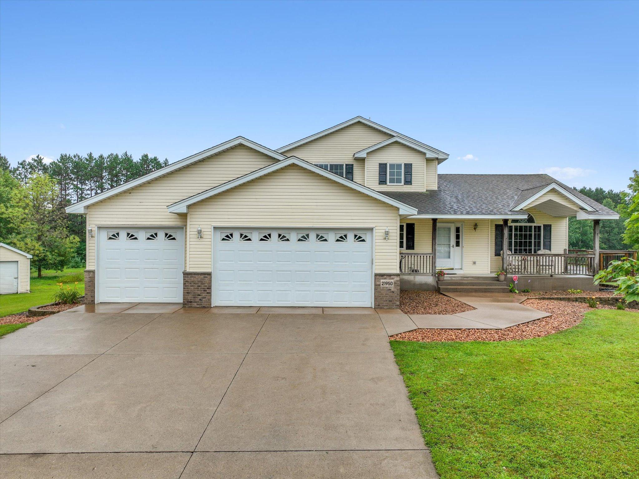Spacious front exterior view showcases the home’s inviting covered porch, attached three-car garage, and peaceful cul-de-sac setting surrounded by open acreage.