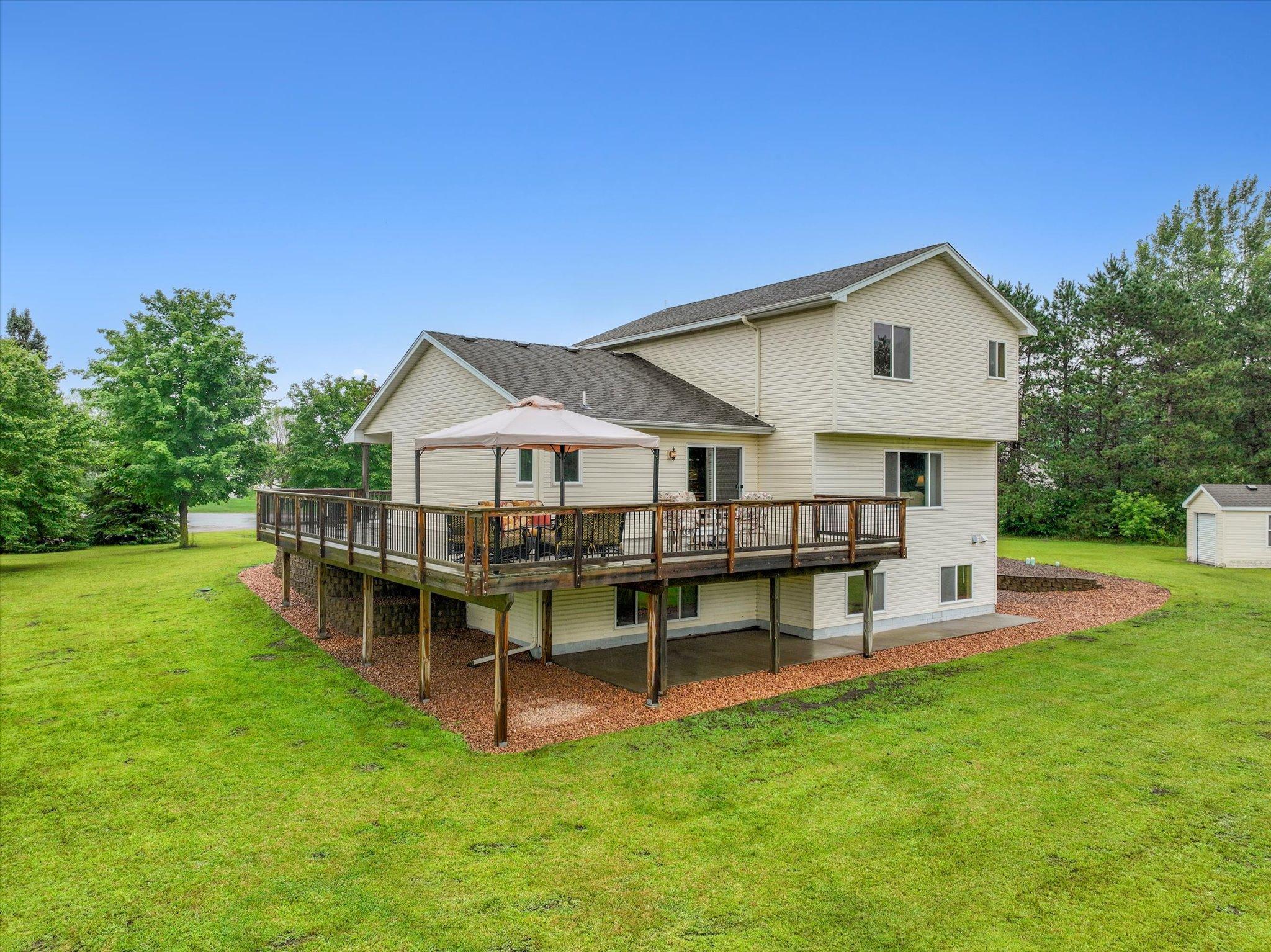 Expansive wraparound deck provides substantial outdoor living space overlooking the private backyard.
