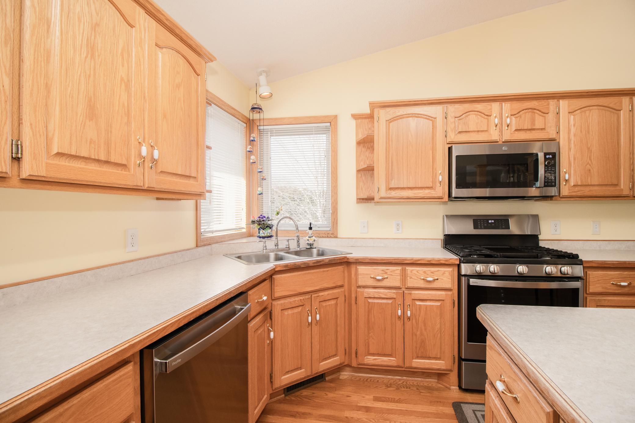 Functional kitchen layout offers generous counter space, hardwood flooring, and corner window placement bringing in natural light above the sink.