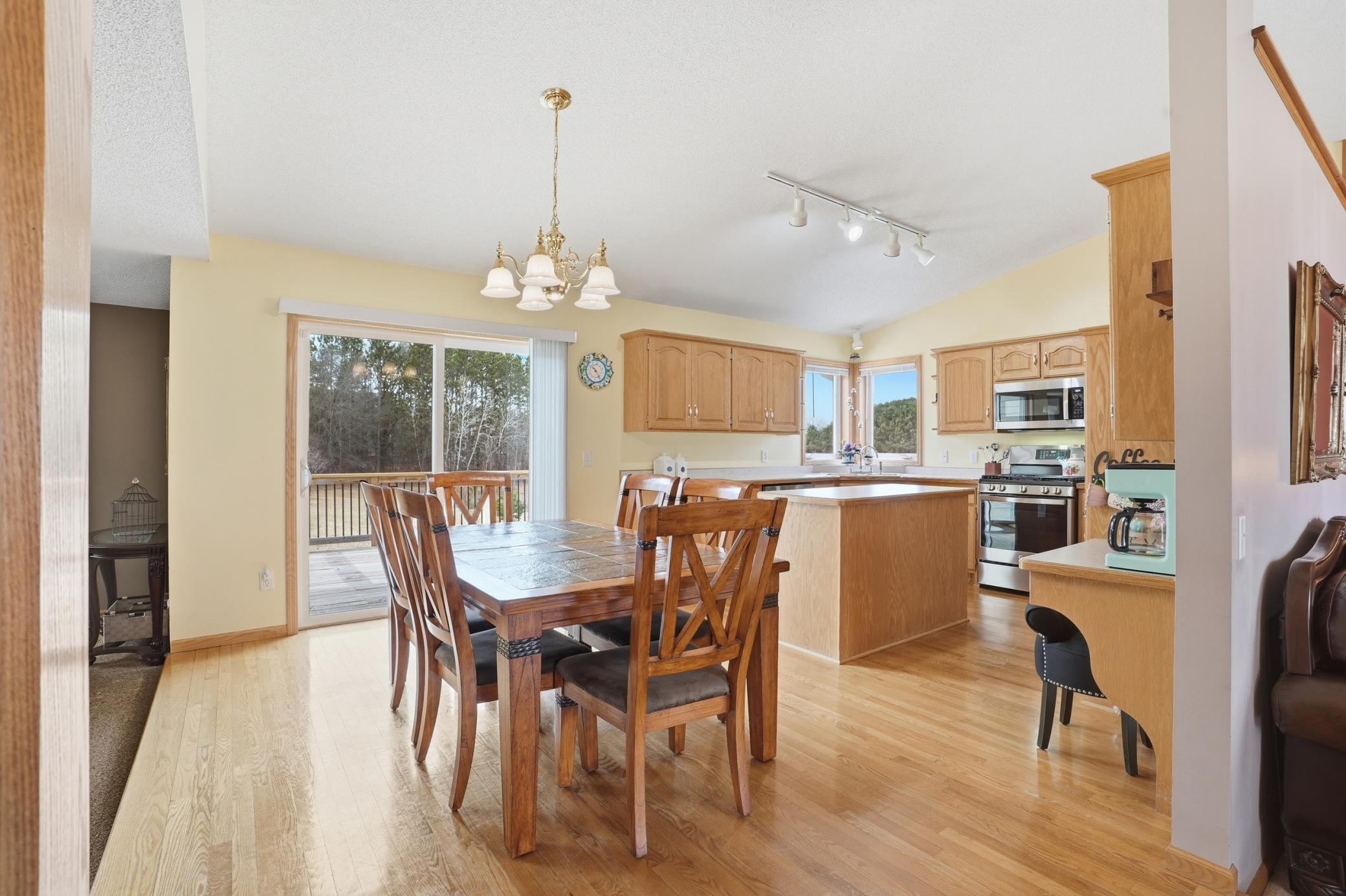 Bright open dining area with hardwood floors and seamless flow to the kitchen and deck beyond.