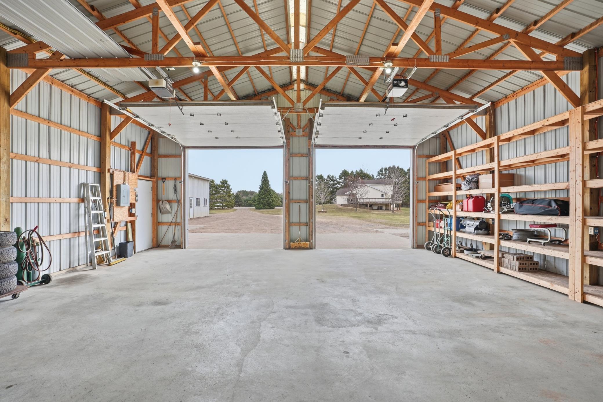 Secondary outbuilding interior features tall ceilings, open-span access, built-in shelving, and oversized door clearance.