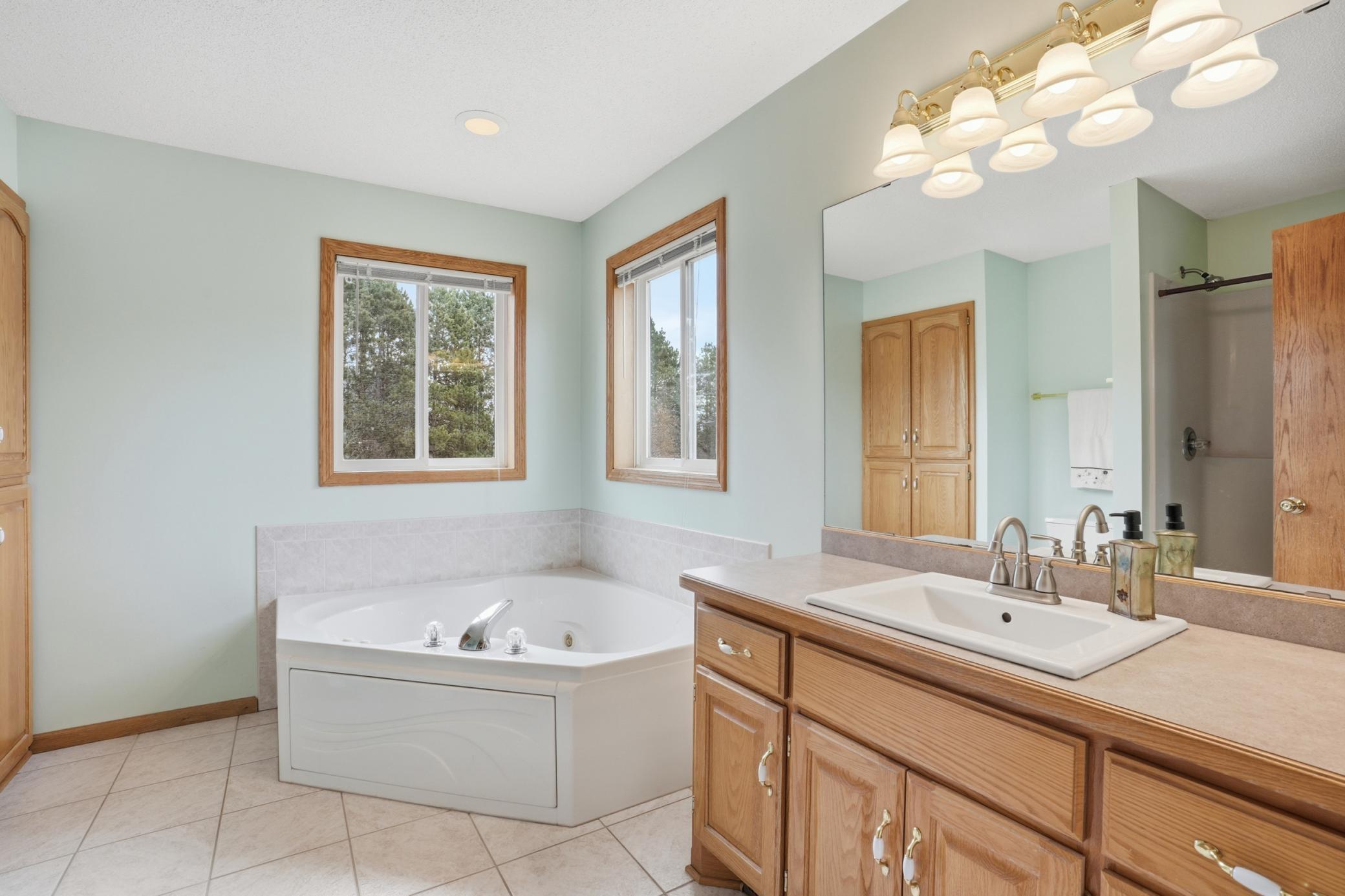 Private primary bath featuring soaking tub, large vanity, and bright natural light.