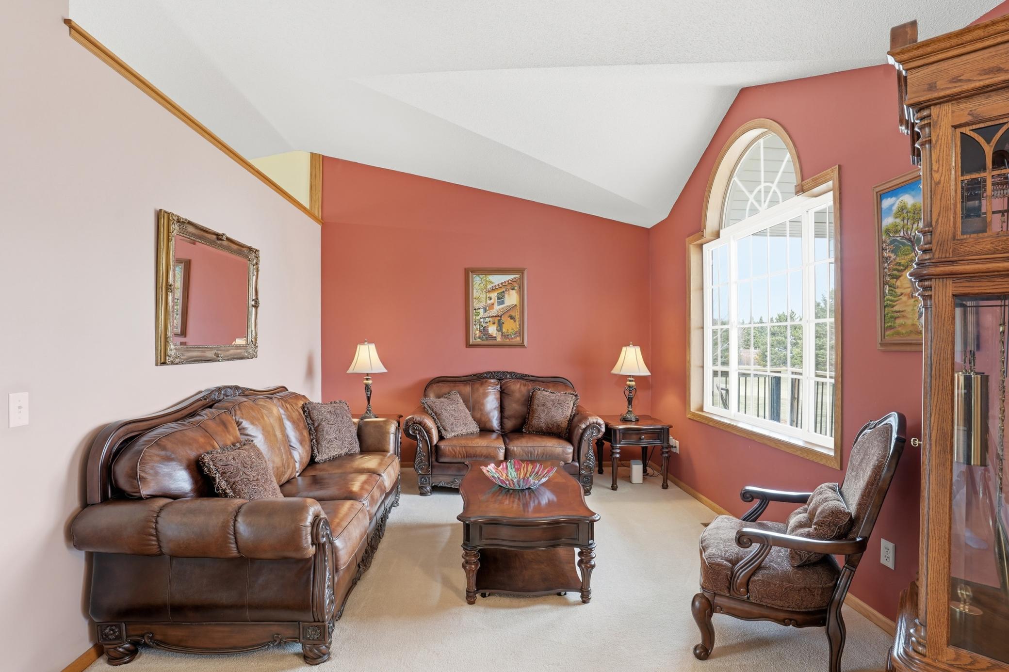 Inviting front living room with vaulted ceilings, oversized arched window, and abundant natural light.