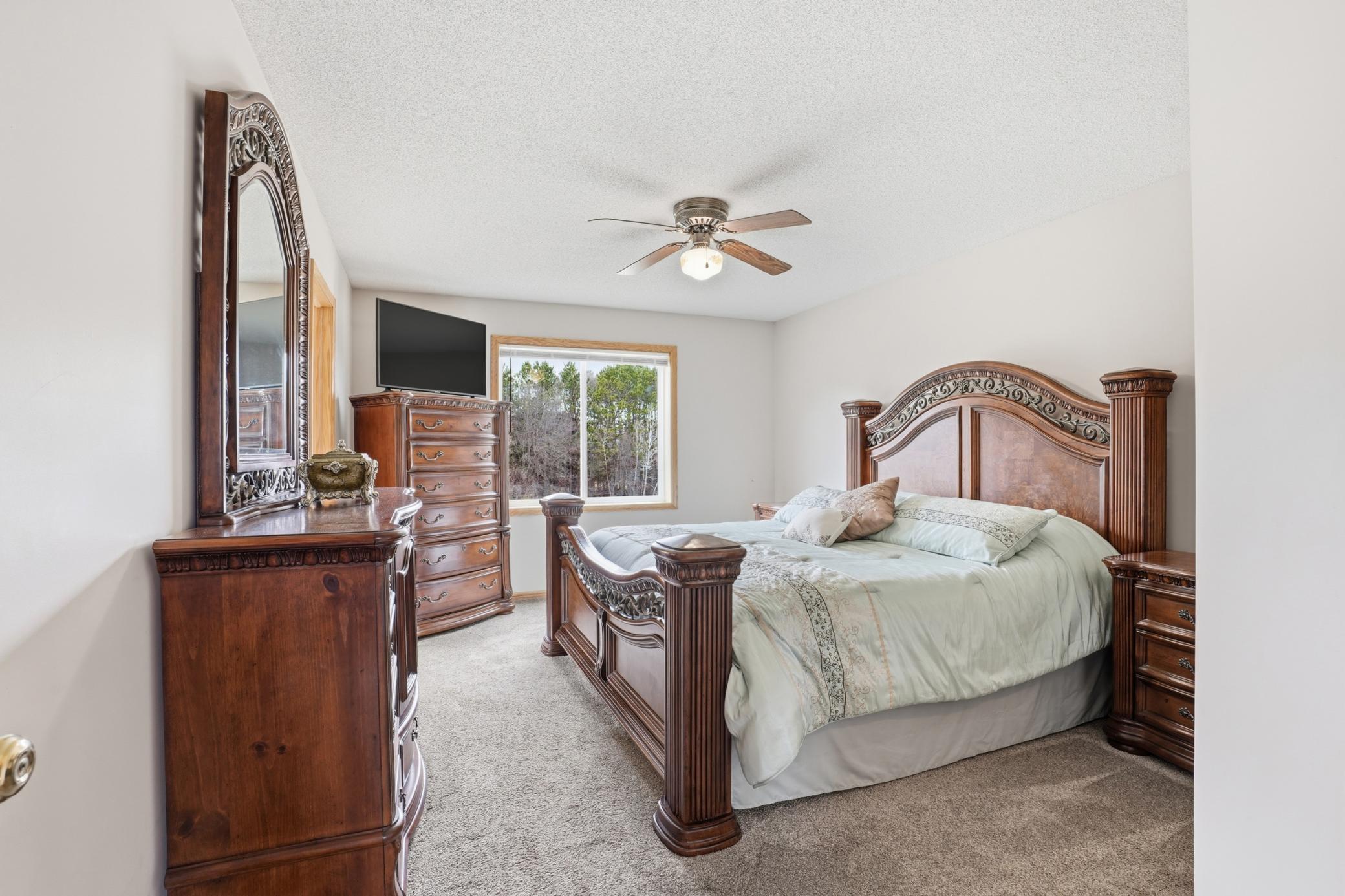 Spacious primary bedroom retreat with large picture window, plush carpeting, and elegant furnishings.