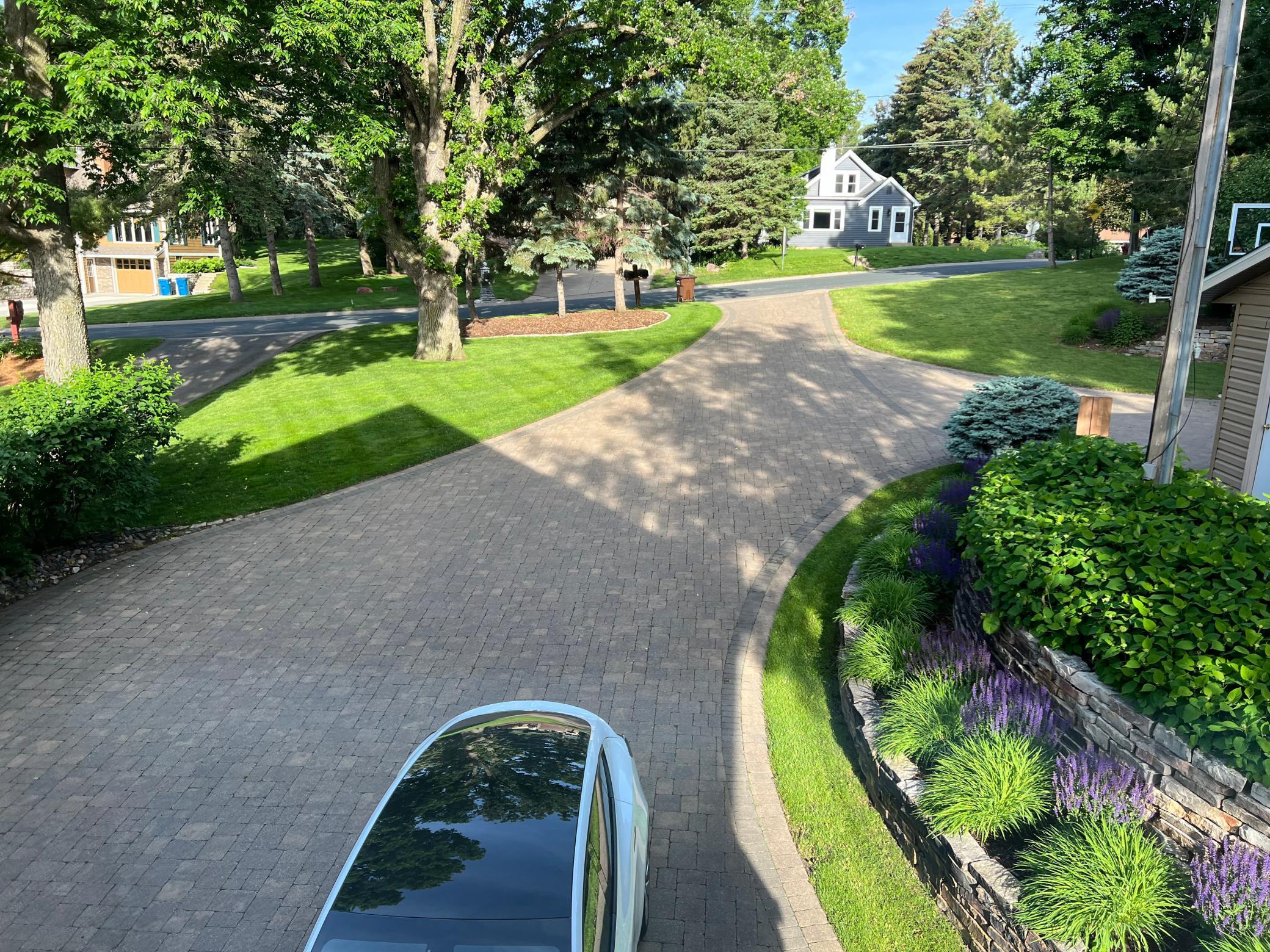 The paver driveway is surrounded by the well kept lawn and perennials on the retaining wall. Plenty of parking for guests too.