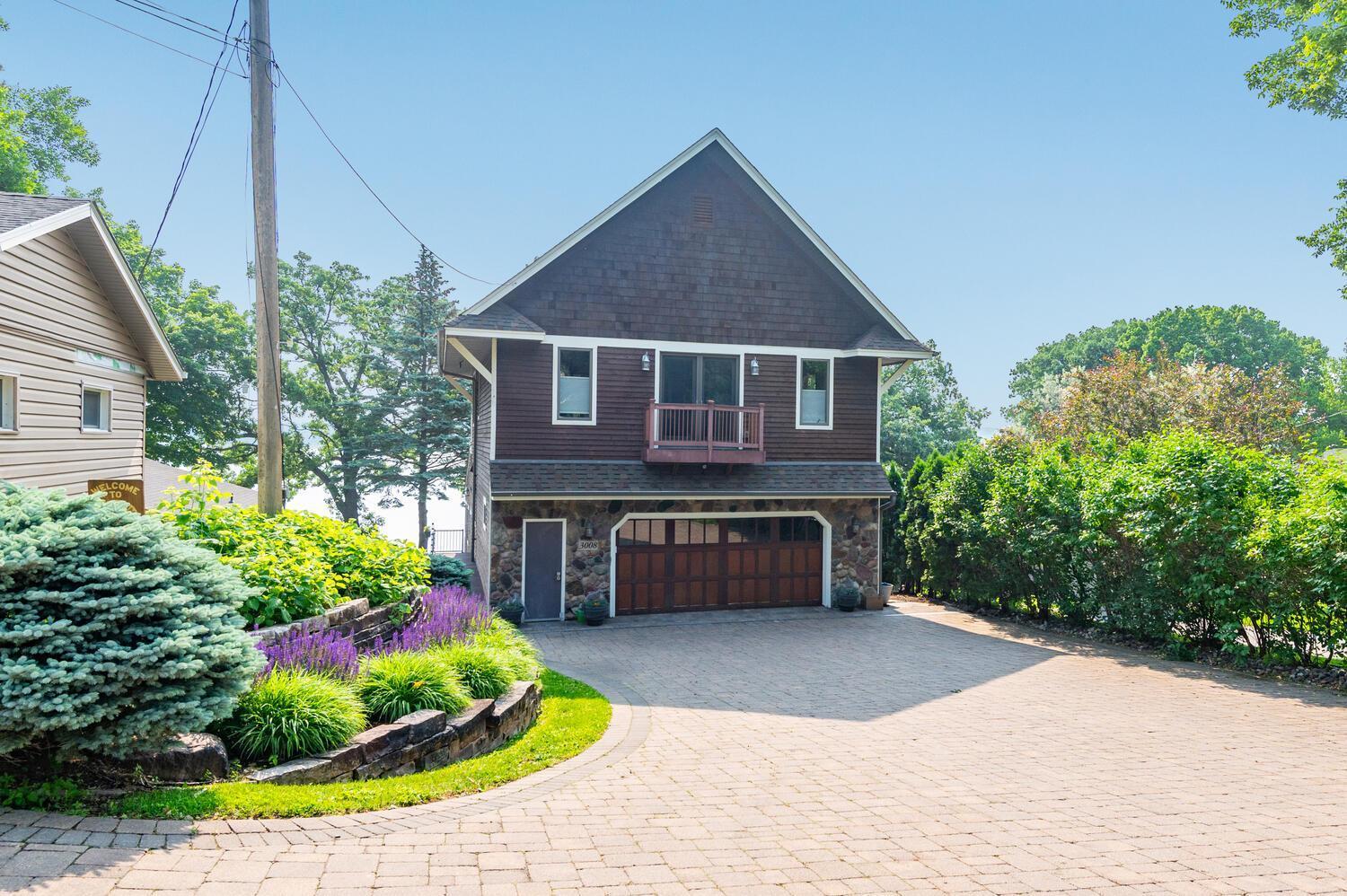 The front of the home with stone retaining walls, wonderful landscaping and paver driveway.