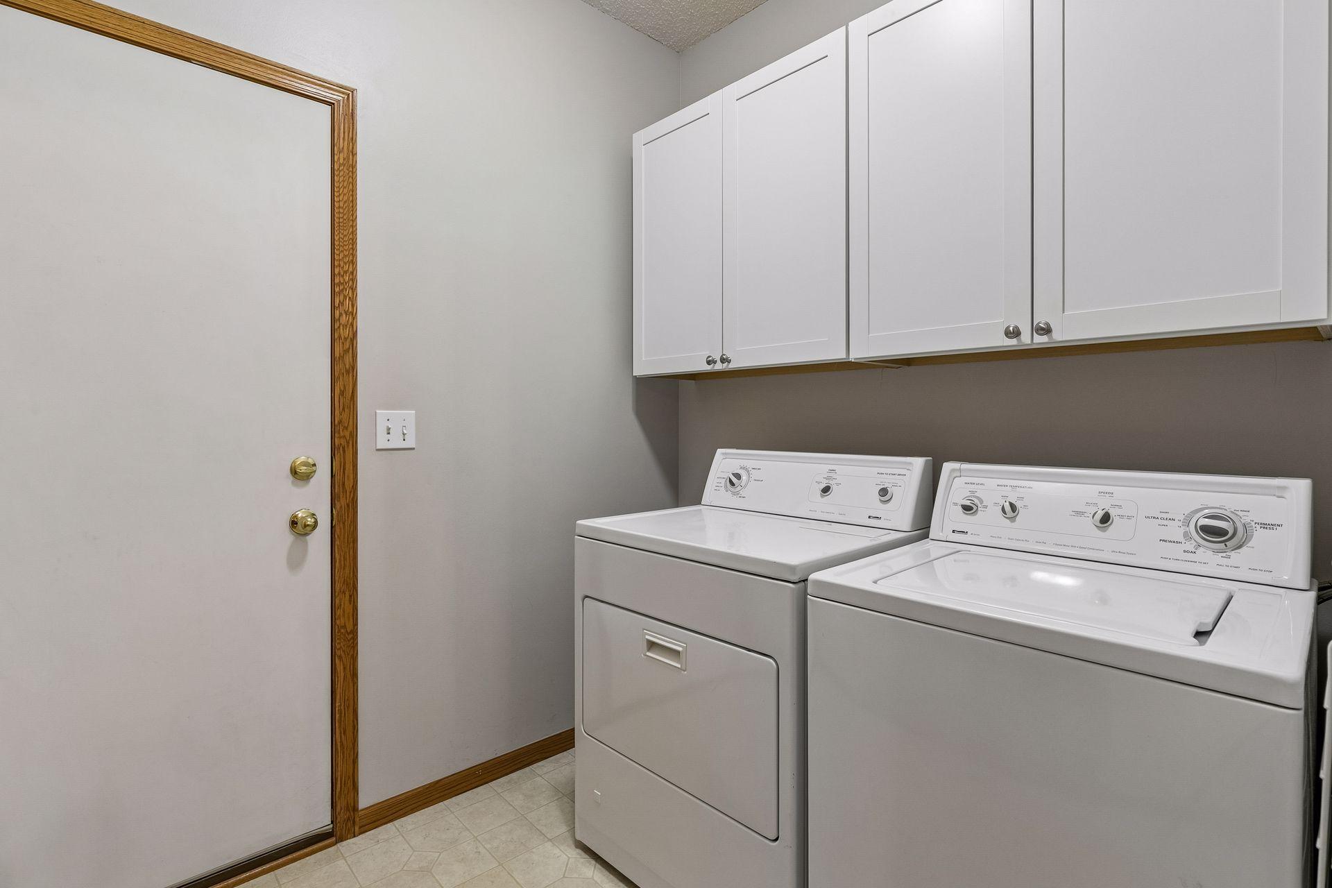 Main-level laundry room /mudroom with upper storage cabinets, a large closet and direct access to the garage for everyday convenience.