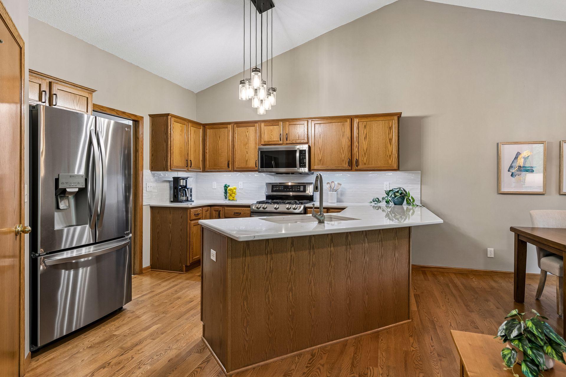 Updated kitchen with quartz countertops, stainless steel appliances, subway tile backsplash, center island with seating, abundant cabinetry and vaulted ceilings. Perfect for cooking and gathering.
