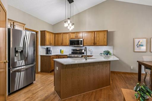 Updated kitchen with quartz countertops, stainless steel appliances, subway tile backsplash, center island with seating, abundant cabinetry and vaulted ceilings. Perfect for cooking and gathering.