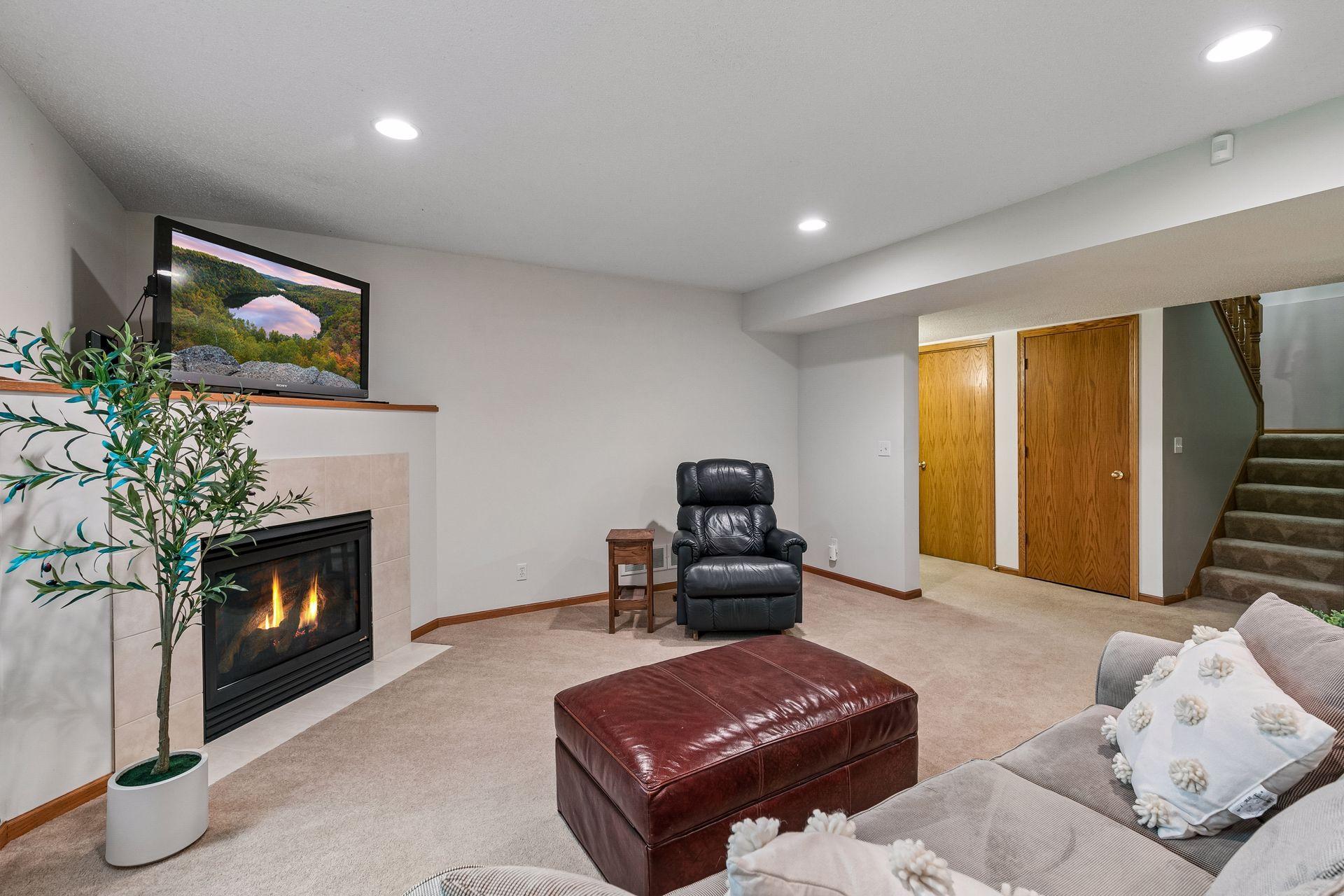 Finished walkout lower level featuring a large family room with fireplace, neutral finishes, recessed lighting, and comfortable living space for guests or everyday enjoyment.