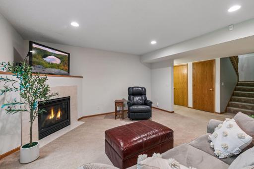 Finished walkout lower level featuring a large family room with fireplace, neutral finishes, recessed lighting, and comfortable living space for guests or everyday enjoyment.