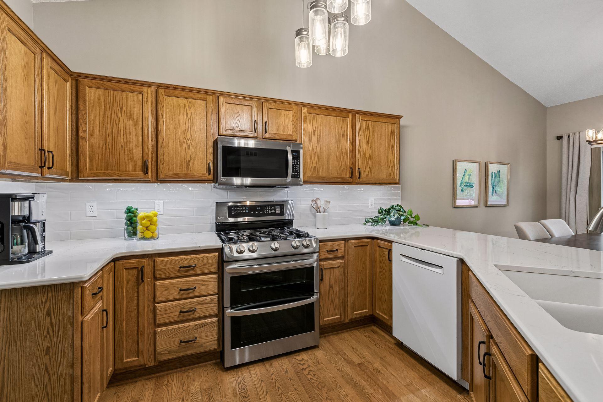 Stylish kitchen featuring quartz surfaces, gas range, stainless steel appliances, and generous prep space. Open-concept design connects directly to dining and living areas for easy entertaining.