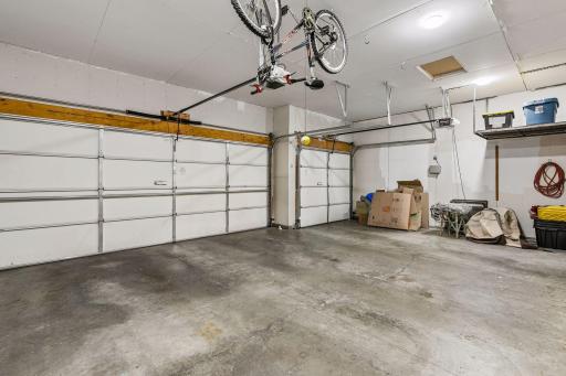 Oversized insulated 3-car garage with high ceilings, hanging bike storage, and additional wall shelving for extra convenience and functionality