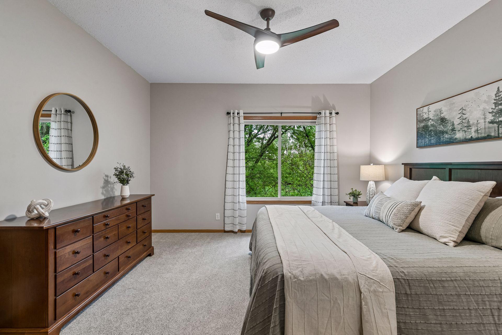 Bright and inviting primary suite featuring soft carpet, wooded views, and a spacious layout with room for additional seating or furniture.