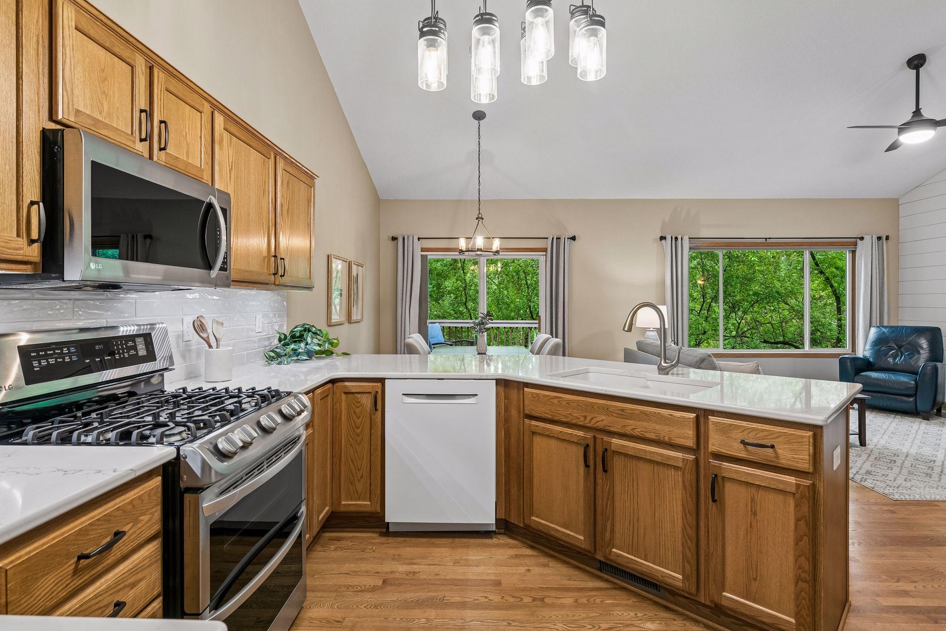 Spacious kitchen with quartz countertops, stainless steel appliances, breakfast bar seating area, hardwood flooring, open to the main living space. Ideal for buyers searching for move-in-ready homes in Eagan with functional one-level living.