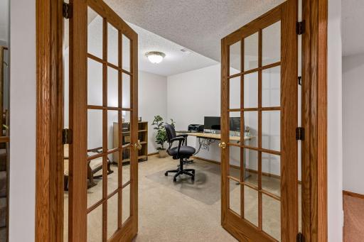 Private lower-level office or hobby room with elegant French doors, soft carpet, and flexible space ideal for working from home, crafts, or a quiet retreat.