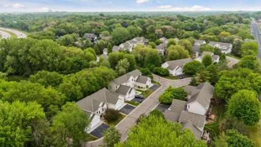 Aerial view showcasing the beautiful Woodstone neighborhood surrounded by mature trees, walking paths, and convenient access to major roads and daily amenities.