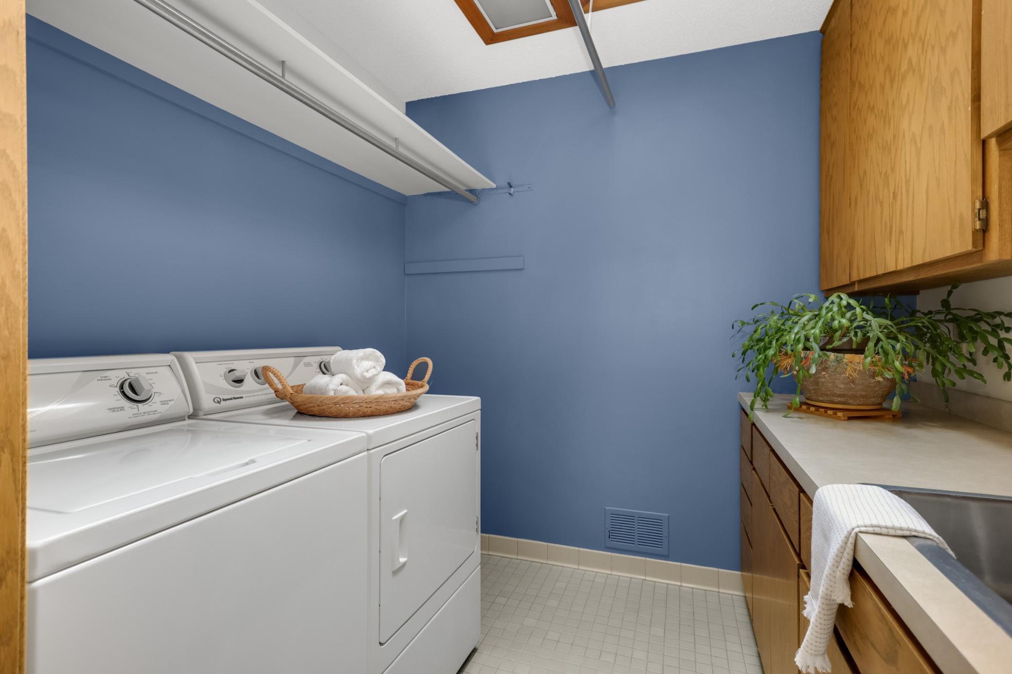 Convenient upper-level laundry room with a utility sink, ample storage and a skylight that fills the space with natural light.