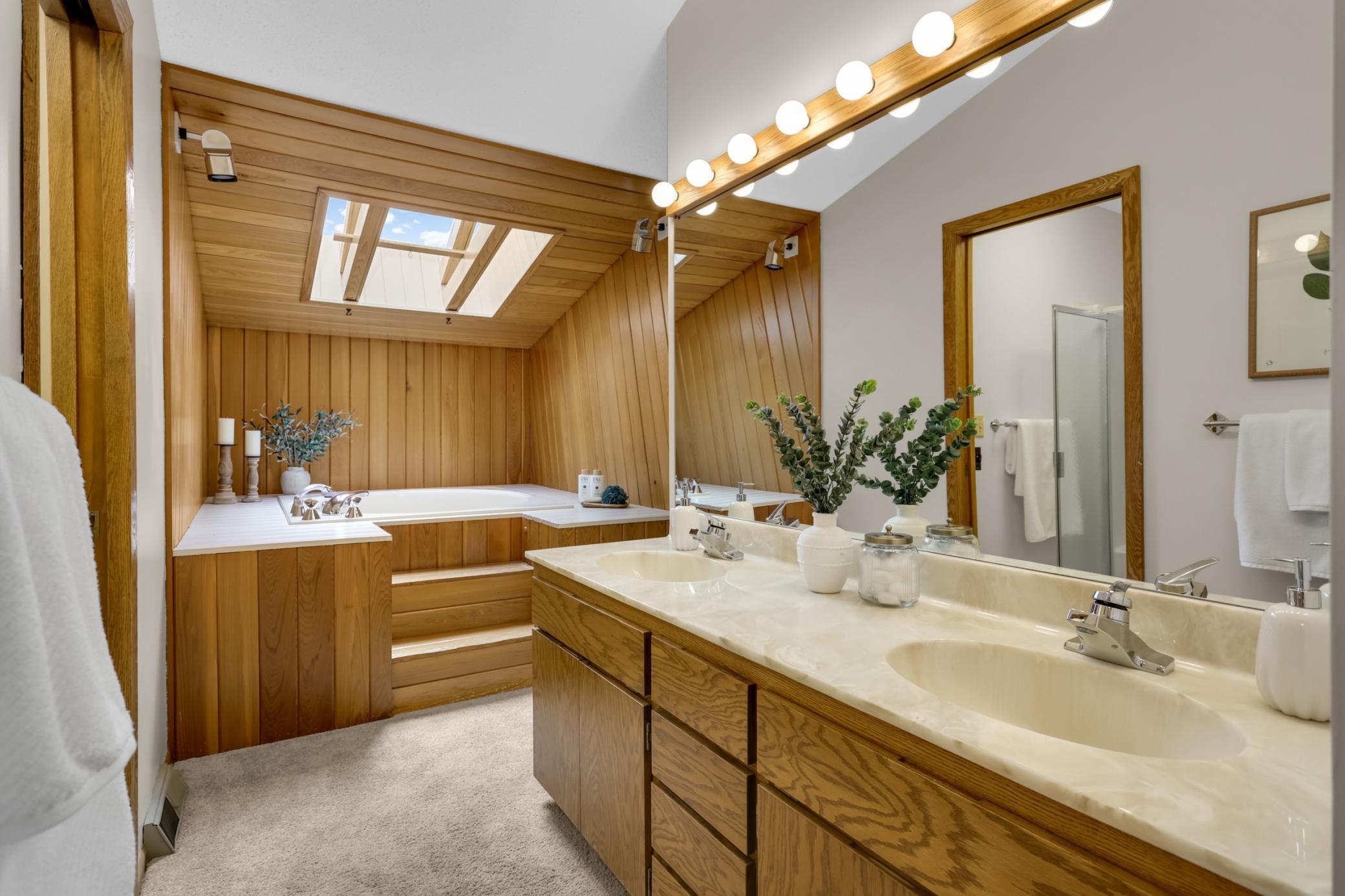 The spacious primary bath features a double vanity, separate shower and an oversized soaking tub beneath a skylight.