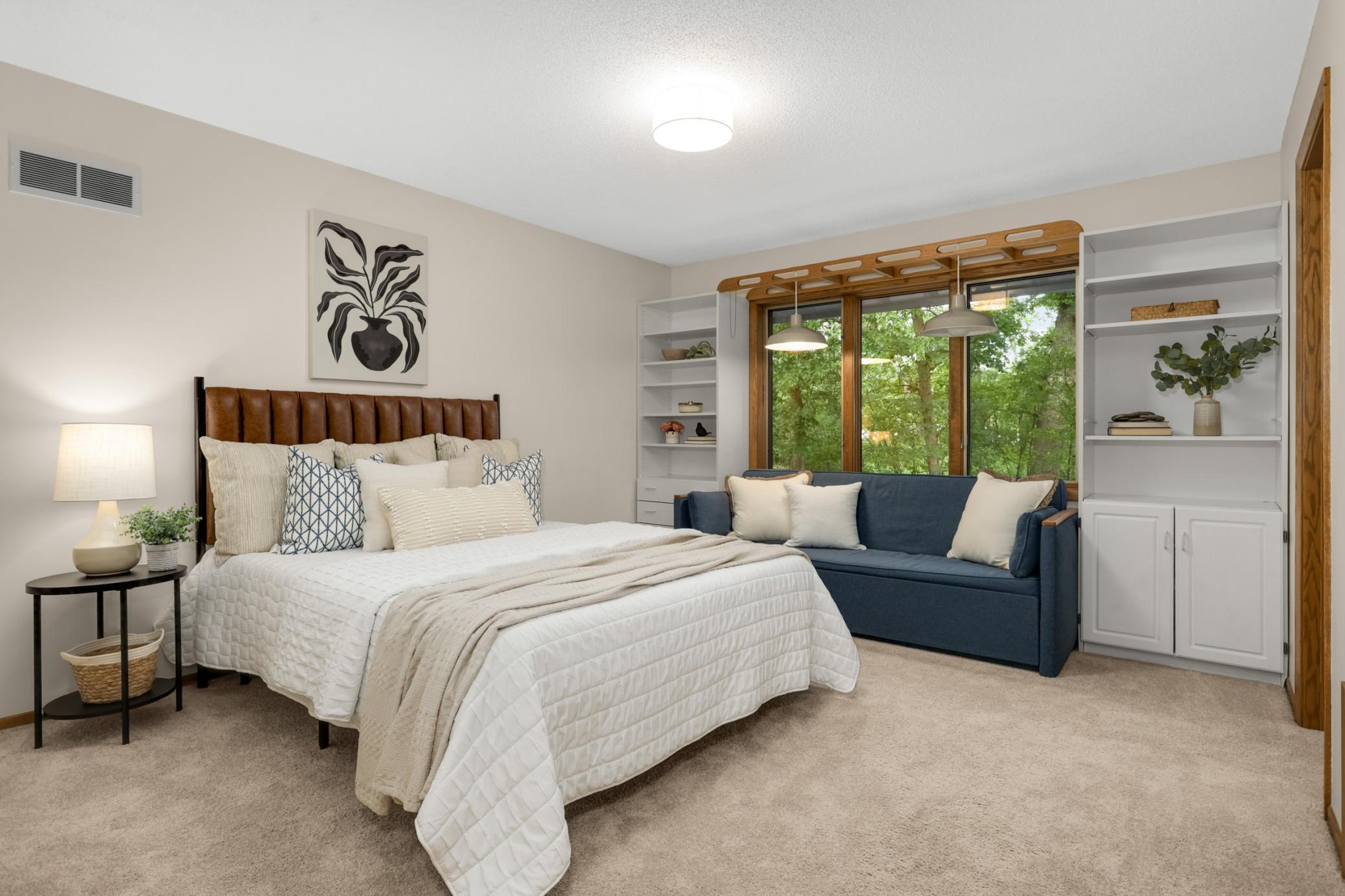 The spacious second bedroom features built-in shelving, generous natural light and peaceful views of the surrounding trees.