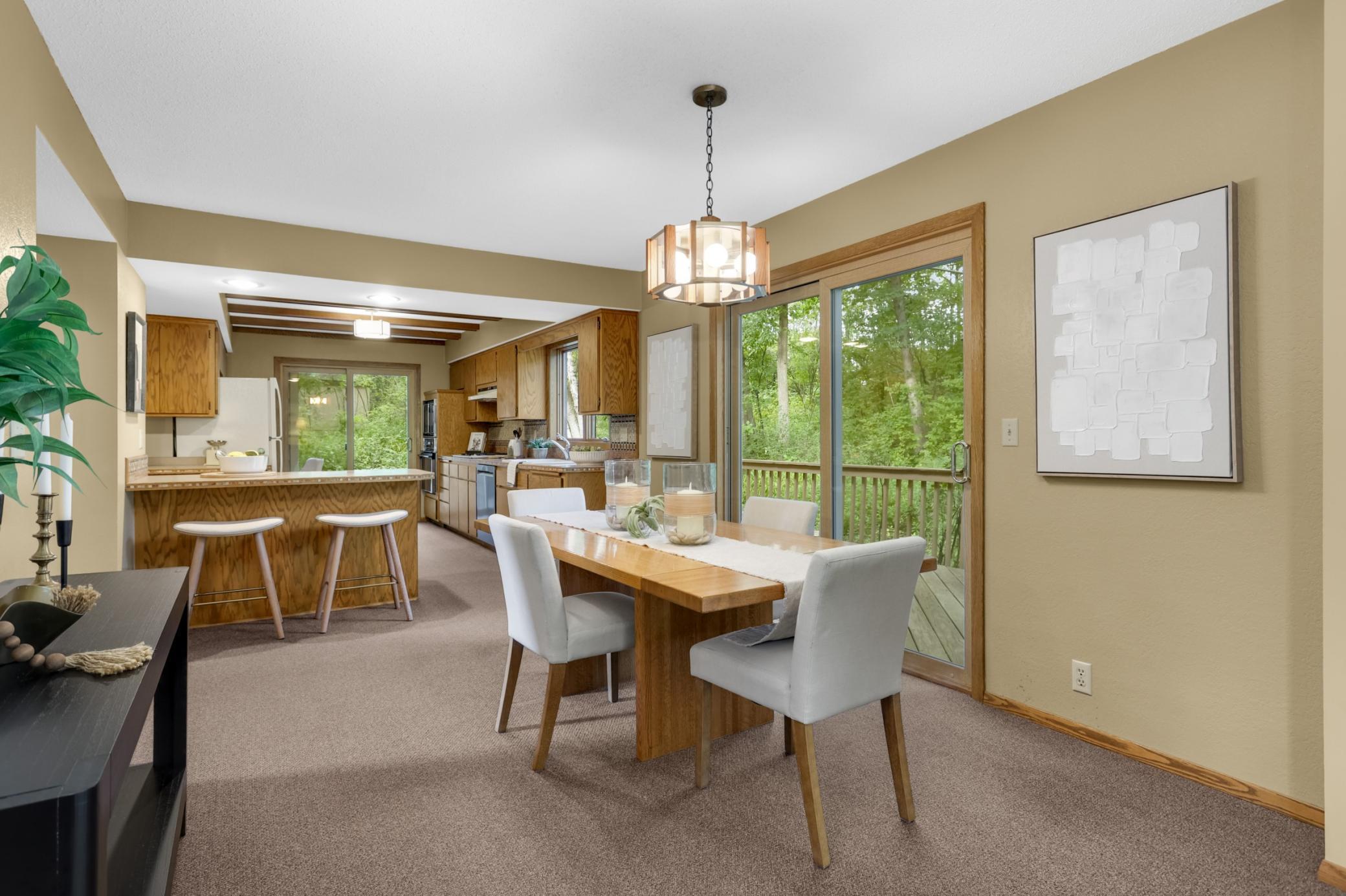 The dining area flows seamlessly into the kitchen, creating an inviting space for everyday meals and effortless entertaining, with peaceful wooded views just beyond the sliding glass doors.