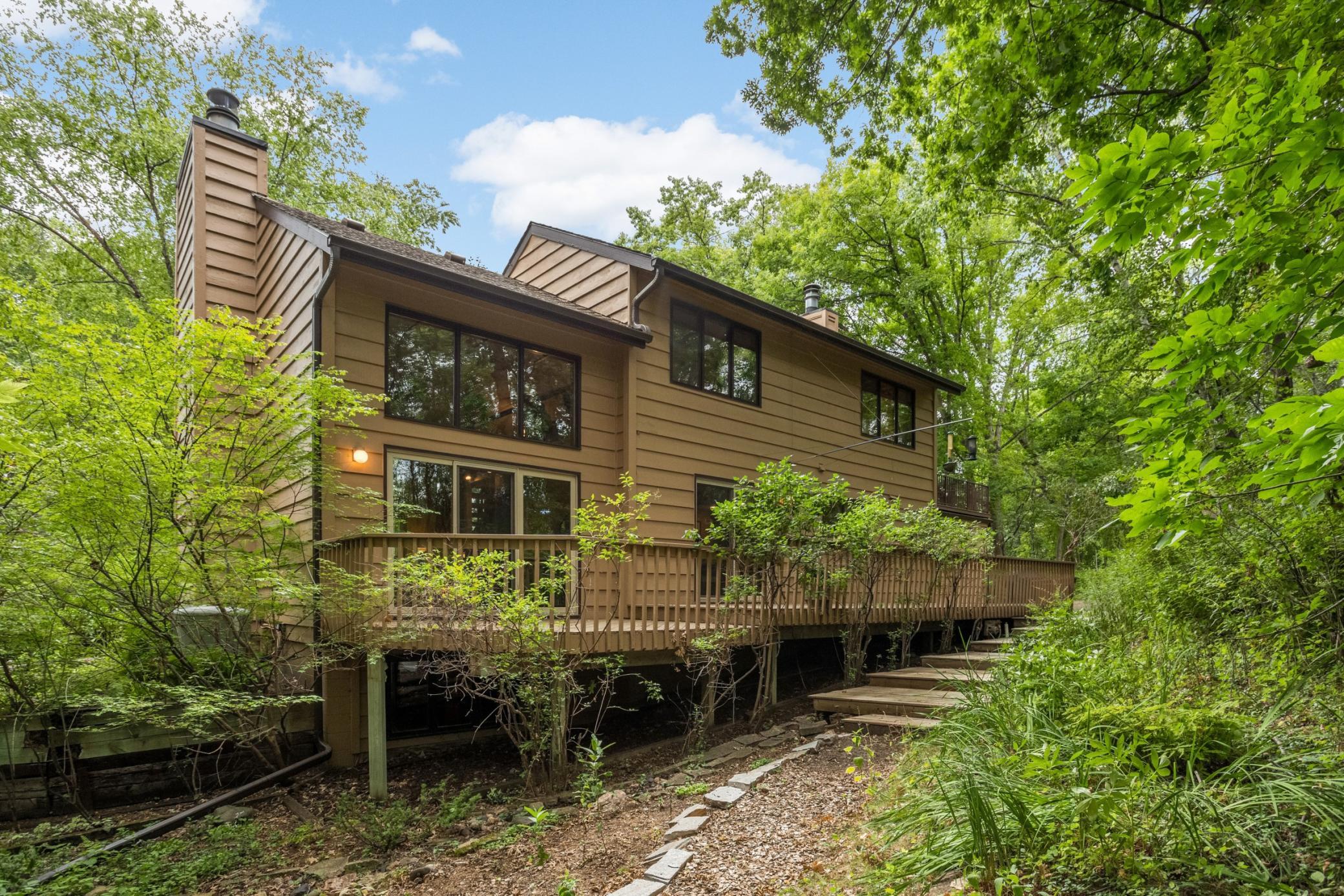 An expansive deck offers multiple spaces to relax, dine and entertain amid lush, wooded surroundings.