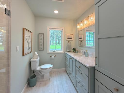 The bathroom features a bright and clean design with a spacious vanity topped with a stone countertop and ample cabinetry for storage.