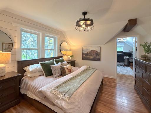 This inviting upper-level bedroom features warm hardwood floors and charming architectural lines created by the angled ceilings.