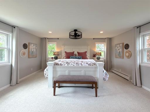 The upper-level primary bedroom is a spacious and relaxing retreat featuring large windows that fill the room with natural light.