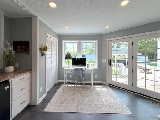 The bright sunroom is filled with natural light with French doors that open to the deck, offering beautiful views of the backyard and pool area.
