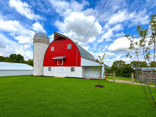 Outbuildings are extensive and versatile, including a 50x104 building, an 80x105 building, a classic 30x50 red barn, a 36x45 six-car garage, and a silo.
