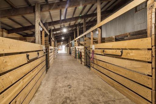 Adjacent areas include a traditional barn section with stalls, storage space, and room for hay, offering a practical setup for livestock or equestrian needs.