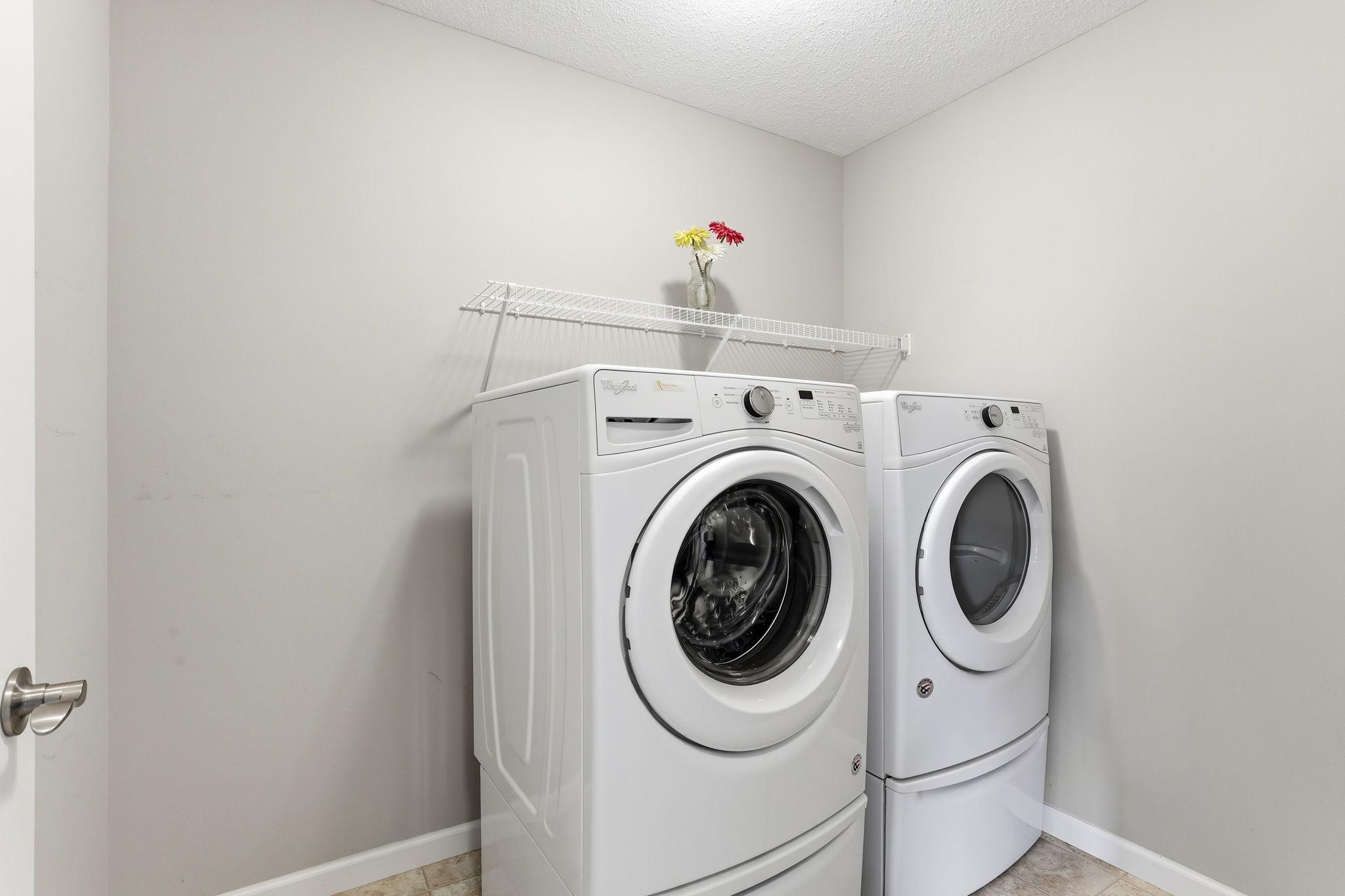 Second-floor laundry is a genuine daily convenience. Front-load washer and dryer on pedestals, wire shelf above, and proximity to all four bedrooms. Exactly where laundry belongs.
