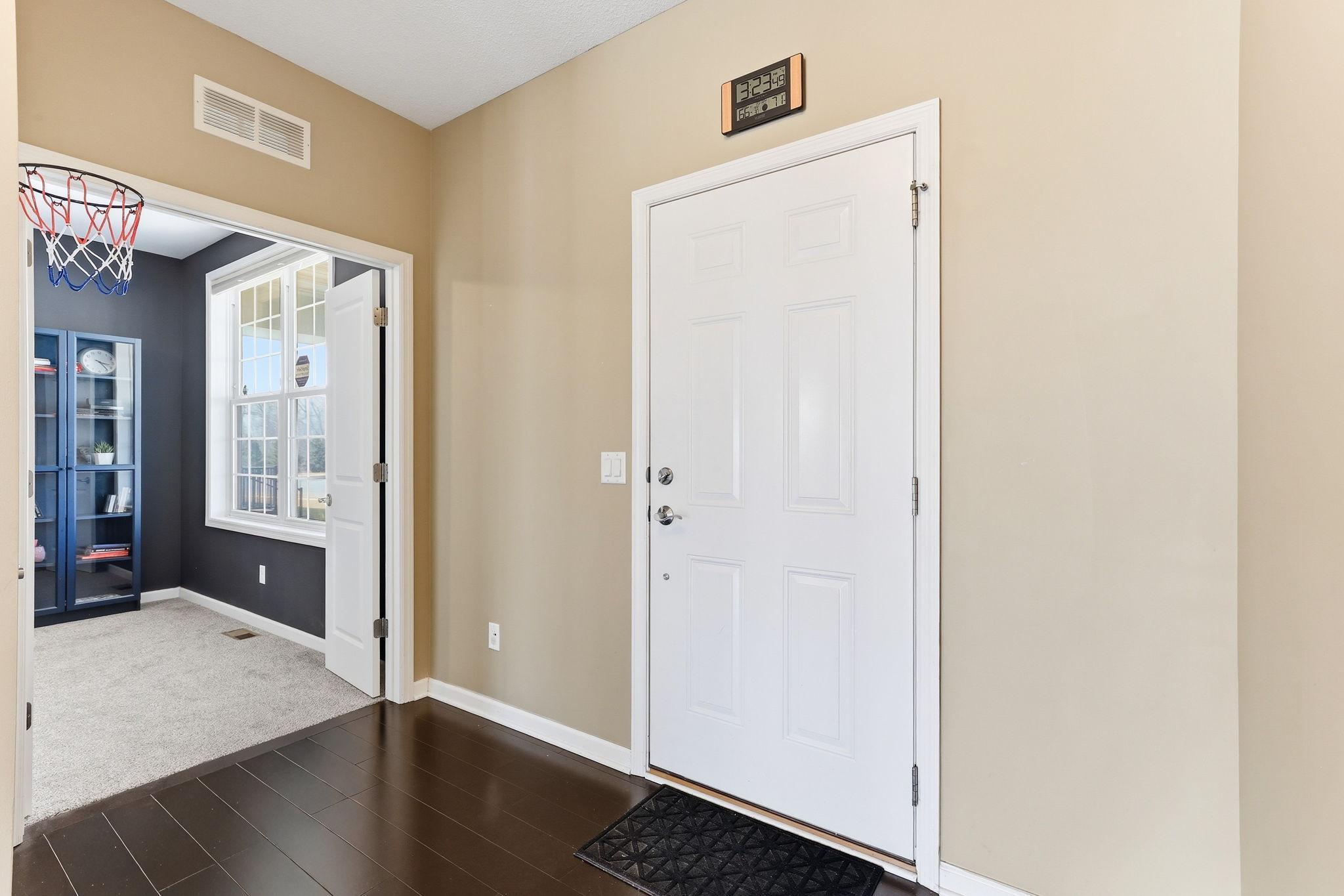 Dark hardwood floors greet you the moment you step inside, setting a refined tone. The front entry opens to a flexible main-floor room on the left and draws the eye toward the living space ahead.