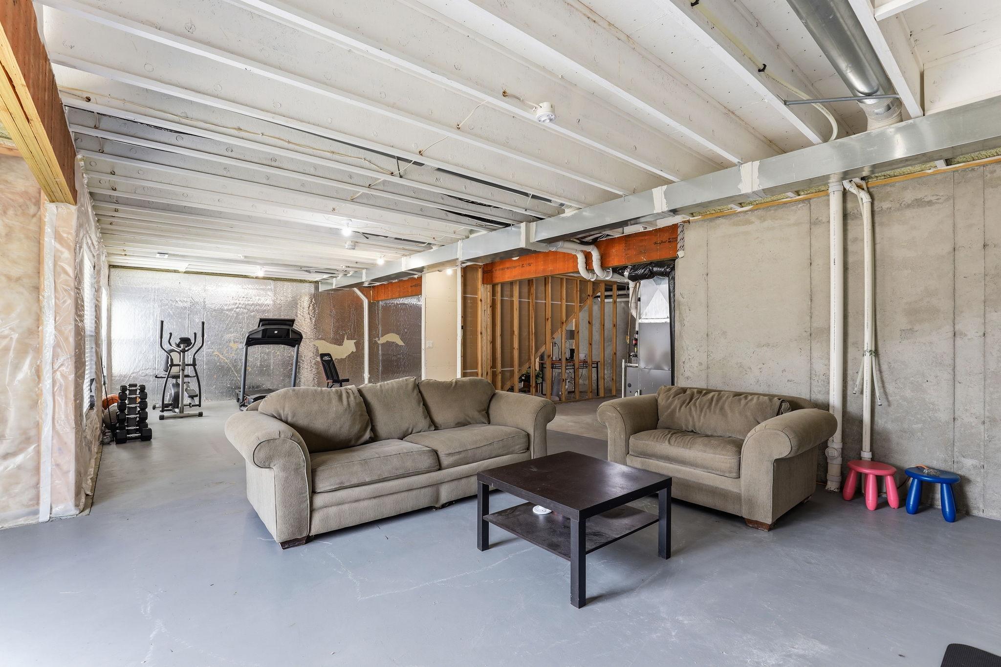 The lower level's scale is remarkable. Separate zones for media and fitness are already in use, and the poured concrete foundation and open floor plan invite a full finish build-out.