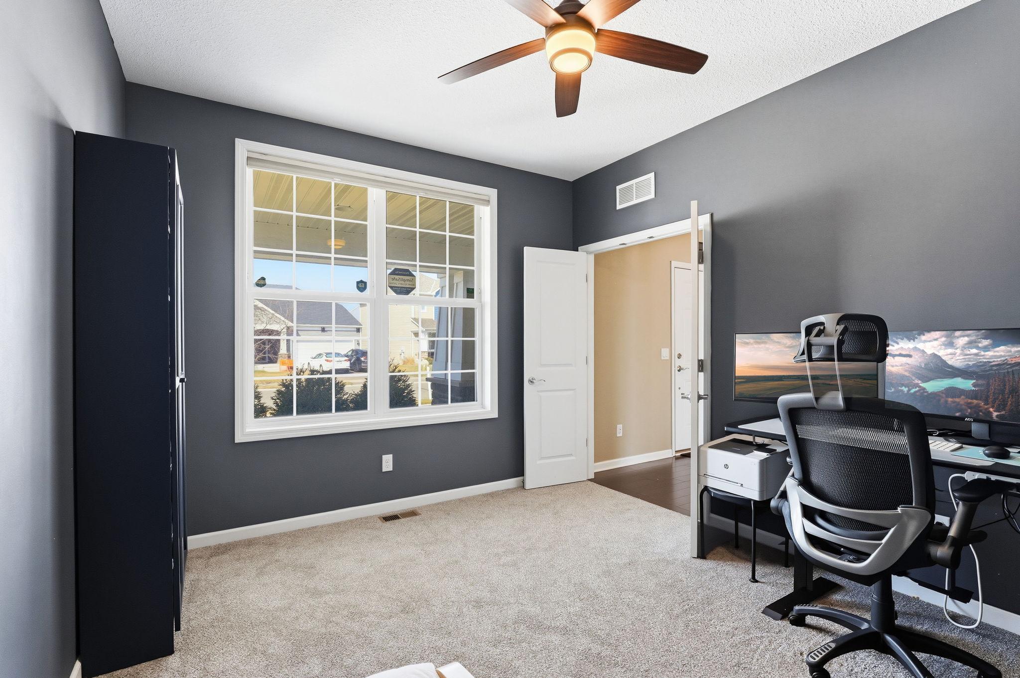 A second angle of the main-floor flex room reveals its generous scale and bright front-facing window. Currently used as a private home office with room for a full workstation setup.