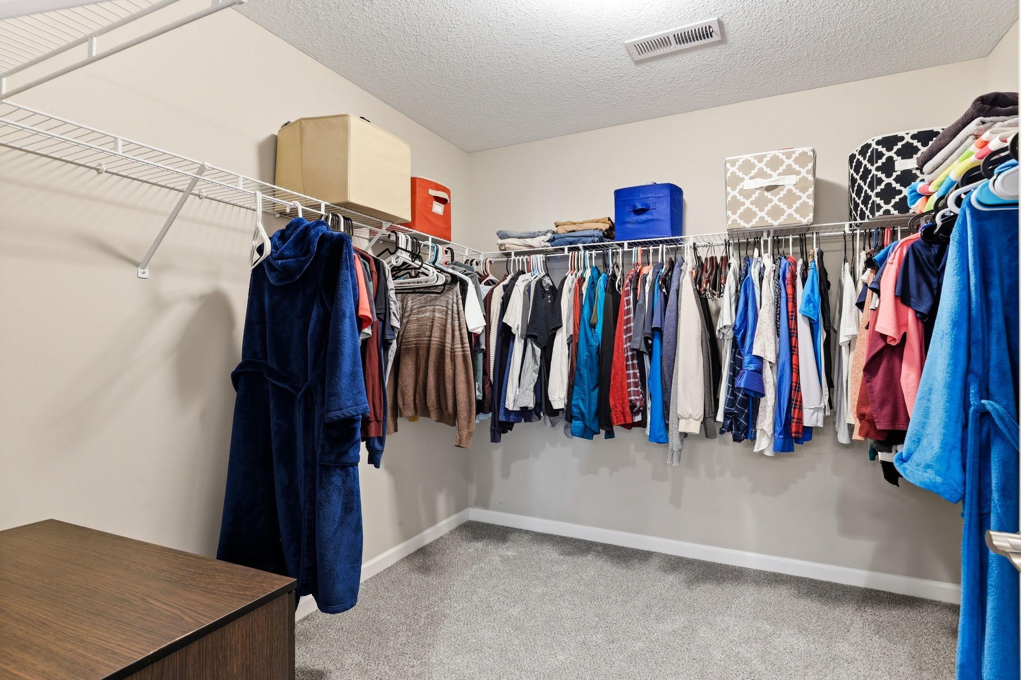 The primary walk-in closet delivers serious capacity: wrap-around wire shelving and hanging rods on three walls. Room enough for two full wardrobes with open floor space to spare.