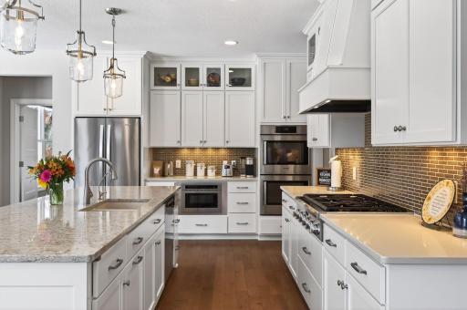 At the center, the stunning kitchen blends beauty and function with high-end stainless steel appliances, including a drawer microwave and convenient side-swing double ovens.