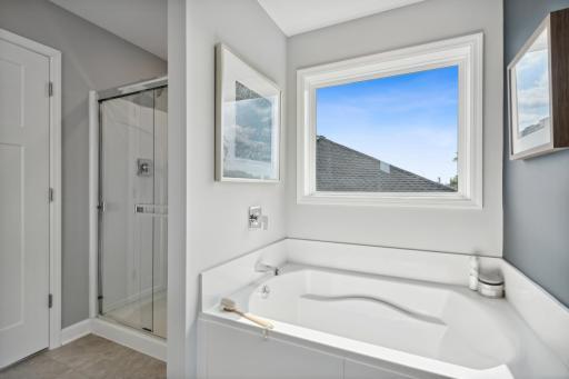 (Photo of a decorated model, actual finishes will vary.) A glass-enclosed shower and separate soaking tub contribute to the bathroom’s spa-like atmosphere.