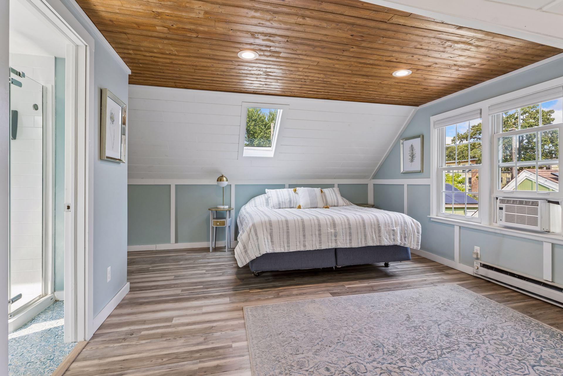 Upper level primary suite with wood slat ceiling and skylights. Newer a/c unit plus supplemental window unit to ensure the upper level stays cool.